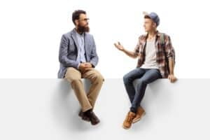 Bearded man and a teenage male student sitting on a panel and talking
